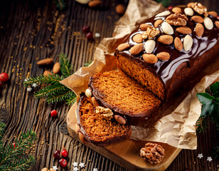 Poster - Gingerbread cake, Christmas gingerbread cake covered with chocolate and decorated with nuts and almonds on the holiday table, copy space, top view. Christmas, traditional dessert