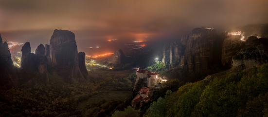 Wall Mural - meteora mountains and monasteries lit at night over kastraki city glowing in distant fog