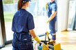Back view on two janitors in blue working uniform clean up roon with panoramic window, wearing yellow rubber gloves