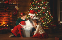 Merry Christmas! Happy Family Mother Father And Children With Magic Gift Near Tree   At Home.