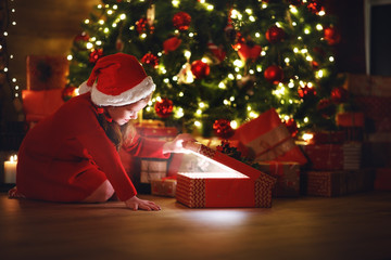 Wall Mural - happy laughing child girl with magic gift on christmas eve.