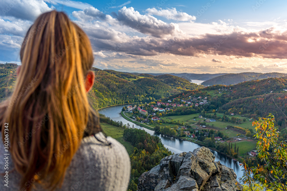 Beautiful girl enjoying life and watching the river, mountains and hills during sunset on the viewpoint (Zduchovice, Solenice, Altán view, hidden gem among travel destinations in Czech republic) - obrazy, fototapety, plakaty 