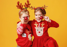 Happy Funny Emotional Children Boy And  Girl In Red Christmas Reindeer Costume  On Yellow   Background.