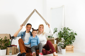 Wall Mural - Happy young family under a safe roof, concept