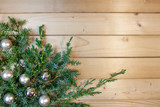 Fototapeta  - Świąteczna dekoracja - gałązki jałowca ozdobione srebrnymi bombkami na tle desek