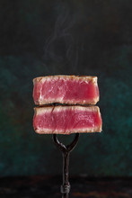 Slices Of Rare Roasted Tuna Steak On Vintage Fork On Dark Background With Copy Space