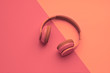 Minimal fashion, Trendy headphones. Music vibration on pink geometry background. Hipster DJ accessory Flat lay. Art creative summer vibes fashionable pop art style. Sweet pastel color, gel filter