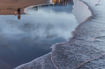 People gazing at the sea waves at sunset in San Sebastian, Spain