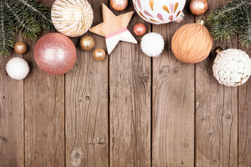 Wall Mural - Christmas top border of dusty rose, gold and white ornaments with branches. Overhead view on a rustic wood background with copy space.