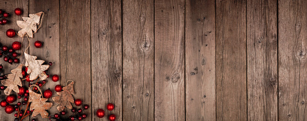 Poster - Christmas corner border banner with wood tree decorations and red baubles. Top view on an rustic wood background.