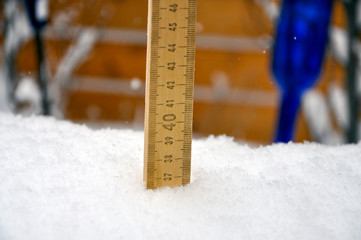 A metre stick registers a huge snowfall in the garden. A decorative blue glass bottle can be seen in the background.