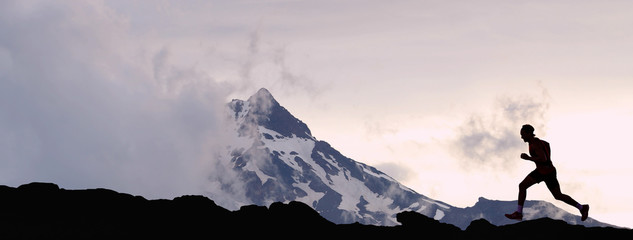 running man athlete trail running in mountain summit background. man on run training outdoors active