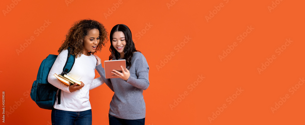 Interracial college students friends looking at tablet computer - obrazy, fototapety, plakaty 