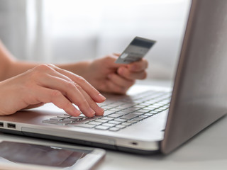 Online shopping concept. Close-up woman's hands holding credit card and using laptop keyboard for online shopping