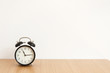 © Emotional design - 白背景　黒い目覚まし時計　木製テーブル　部屋　寝室　背景　グラフィック素材　コピースペース　文字スペース　余白　横　目覚まし　朝　昼　11時　１１時　正面