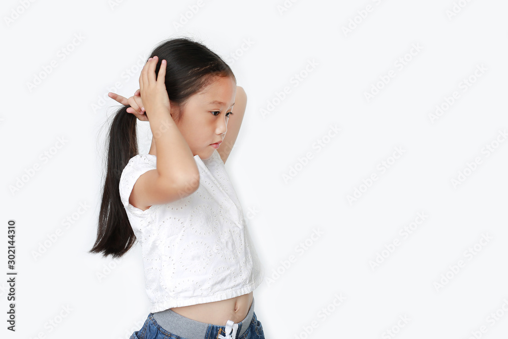 Portrait of little Asian child girl tying her hair by yourself isolated ...