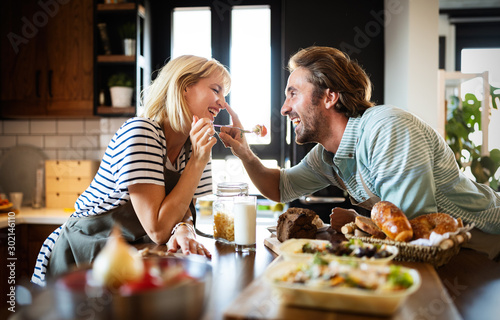 Fotografía Portrait of happy young couple cooking together in the kitchen at home