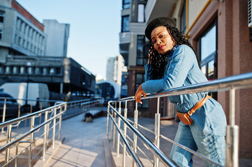 Stylish fashionable african american women in jeans wear and black beret against modern building.