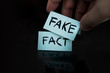 The fact is replaced by a fake. substitution of concepts. a man changes the signs with the words fact on fake on a black background.