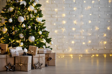 Christmas Tree And Heap Of Gift Boxes - Copy Space Over White Brick Wall With Lights