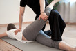 Brunette woman doing stretching on mat with male trainer