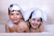 Two kids taking a bath looking a camera