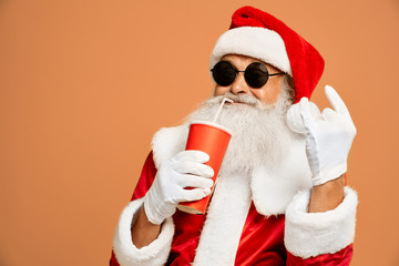 Santa drinking from paper cup and showing two horn sign