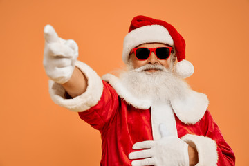 Wall Mural - Senior bearded man in Santa costume pointing on by finger