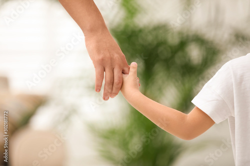 Fotografía Mother holding hands with her child indoors, closeup