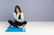 © luismolinero - Young sport woman sitting on the floor with mat unhappy and frustrated