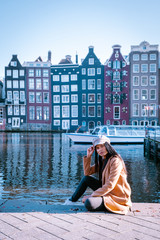 Wall Mural - Young woman in Amsterdam, girl at waterforn in the city of Amsterdam Netherlands