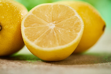 close up view of whole and cut lemons with drops on marble surface