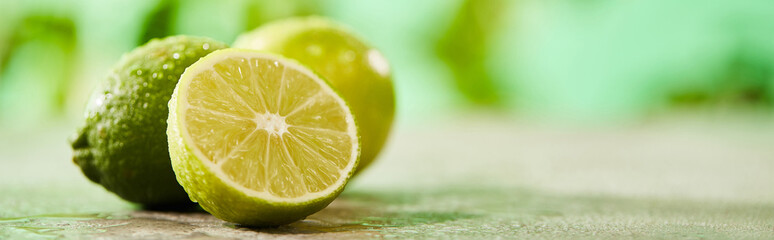 Canvas Print - panoramic shot of whole and cut limes with drops on marble surface