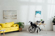 © LIGHTFIELD STUDIOS - Interior of living room with workplace and wheelchair by table