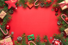 Christmas Frame Made Of Fir Branches, Gift Boxes, Red Holiday Decorations And Candy On Red Background