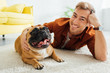 © LIGHTFIELD STUDIOS - Man hugging french bulldog of floor and smiling at camera