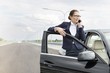 © MDBPIXS - Businesswoman talking on smartphone while standing by car on road