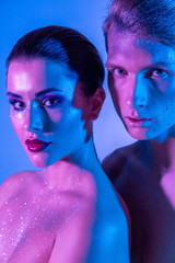 Male and female models in the studio with color filters. Close-up of models in neon purple and blue light