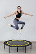 a young girl trains on a mini trampoline is engaged in fitness and stretching on a white  background