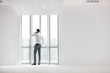 © MDBPIXS - Rear view of businessman standing while talking on smartphone in new office