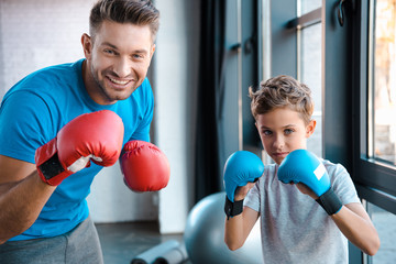 Poster - happy father and cute son in boxing gloves working out in gym