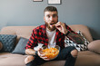 © Drobot Dean - Photo of handsome focused man eating chips while watching sports match