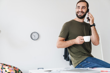 Sticker - Image of caucasian joyful man talking on cellphone and drinking coffee