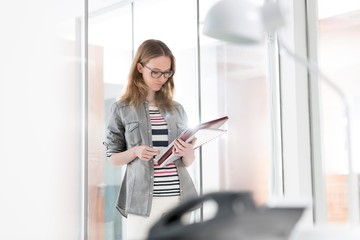 Businesswoman standing while reading document in office