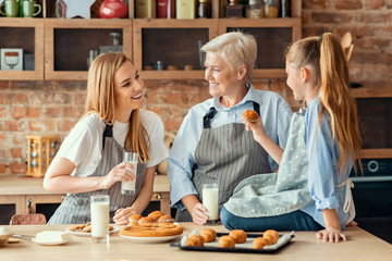 Daughter, mother and grandmother tasting fresh cupcakes at kitchen