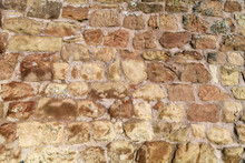 Background With Uneven Old Historic Wall With Brown Irregular Different Sized And Shaped Sandstone Stones In Gray Concrete