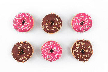 Wall Mural - Six donuts with bright pink and brown chocolate glazing and sugar sprinkles on white background