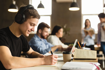 Wall Mural - Student guy preparing for classes, taking notes in library