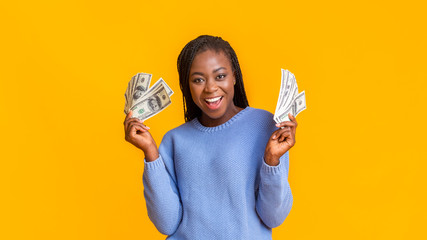 Wall Mural - Happy afro girl with dollar cash over yellow background