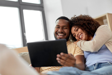 Sticker - mortgage, people and real estate concept - happy african american couple with tablet pc computer sitting on sofa at new home